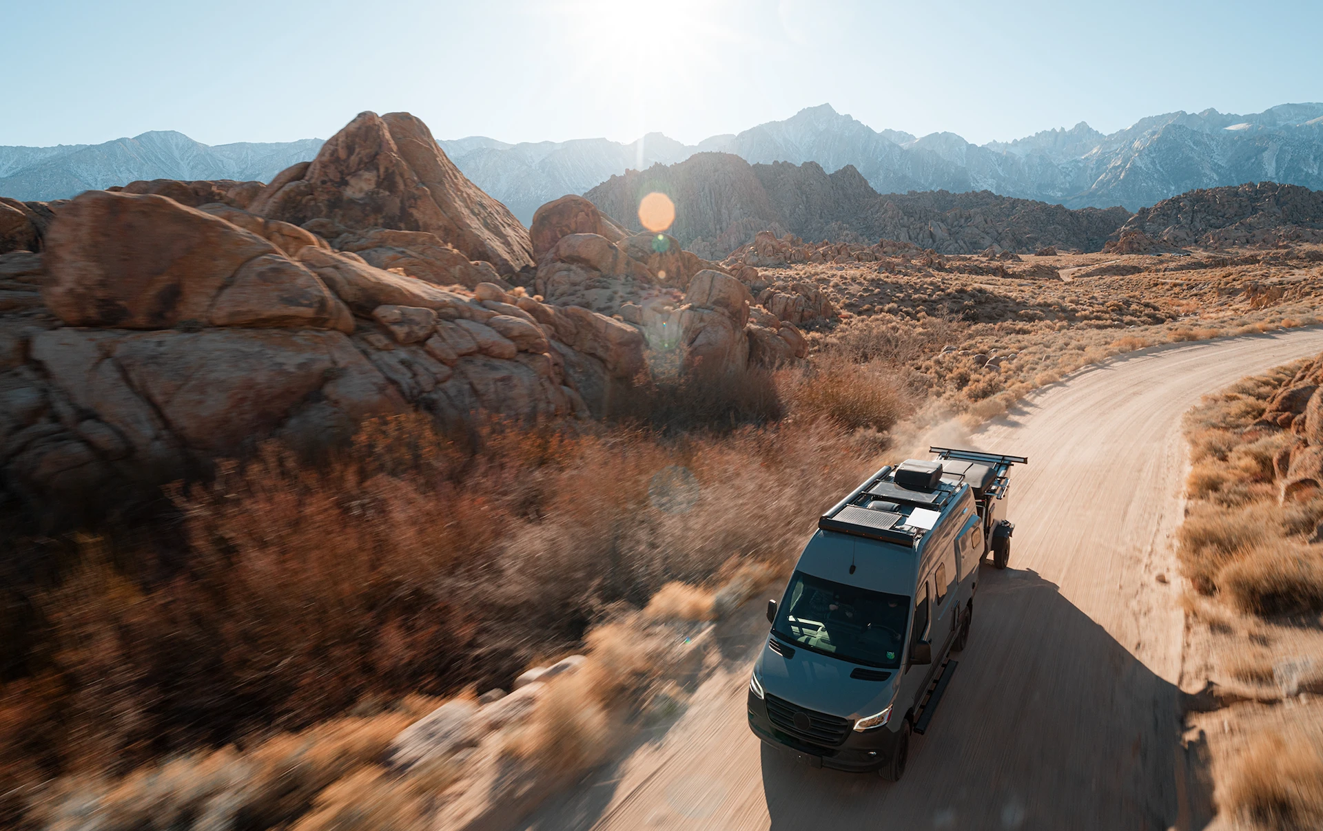 A camper van traveling through a sunlit mountain landscape