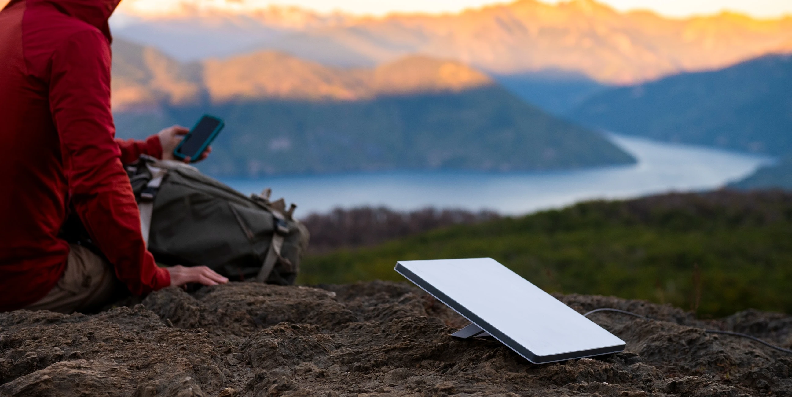 Starlink Mini set up beside a hiker overlooking a mountain lake